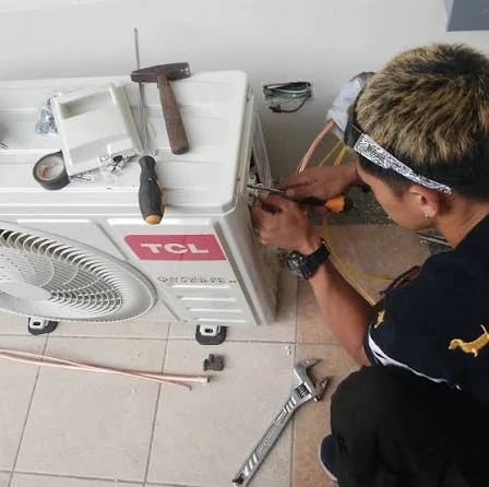 Technician servicing an outdoor air-conditioning unit with hand tools