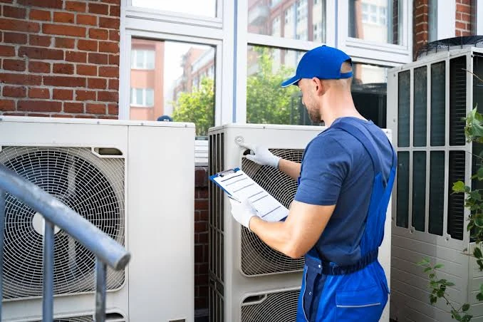 Technician recording readings beside residential outdoor HVAC equipment
