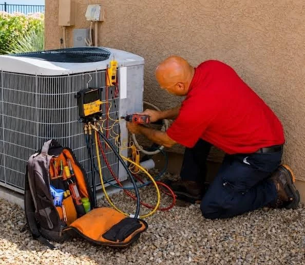 Technician checking an outdoor condenser with connected gauges