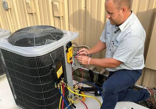 Technician using diagnostic gauges beside an outdoor condenser